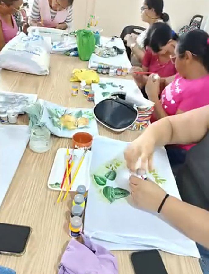 Mesa com participantes pintando panos