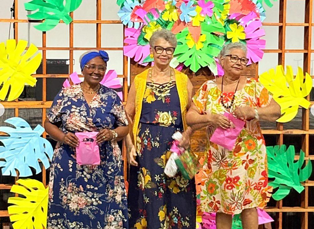 Três irmãs da melhor idade sorrindo com lembrancinhas